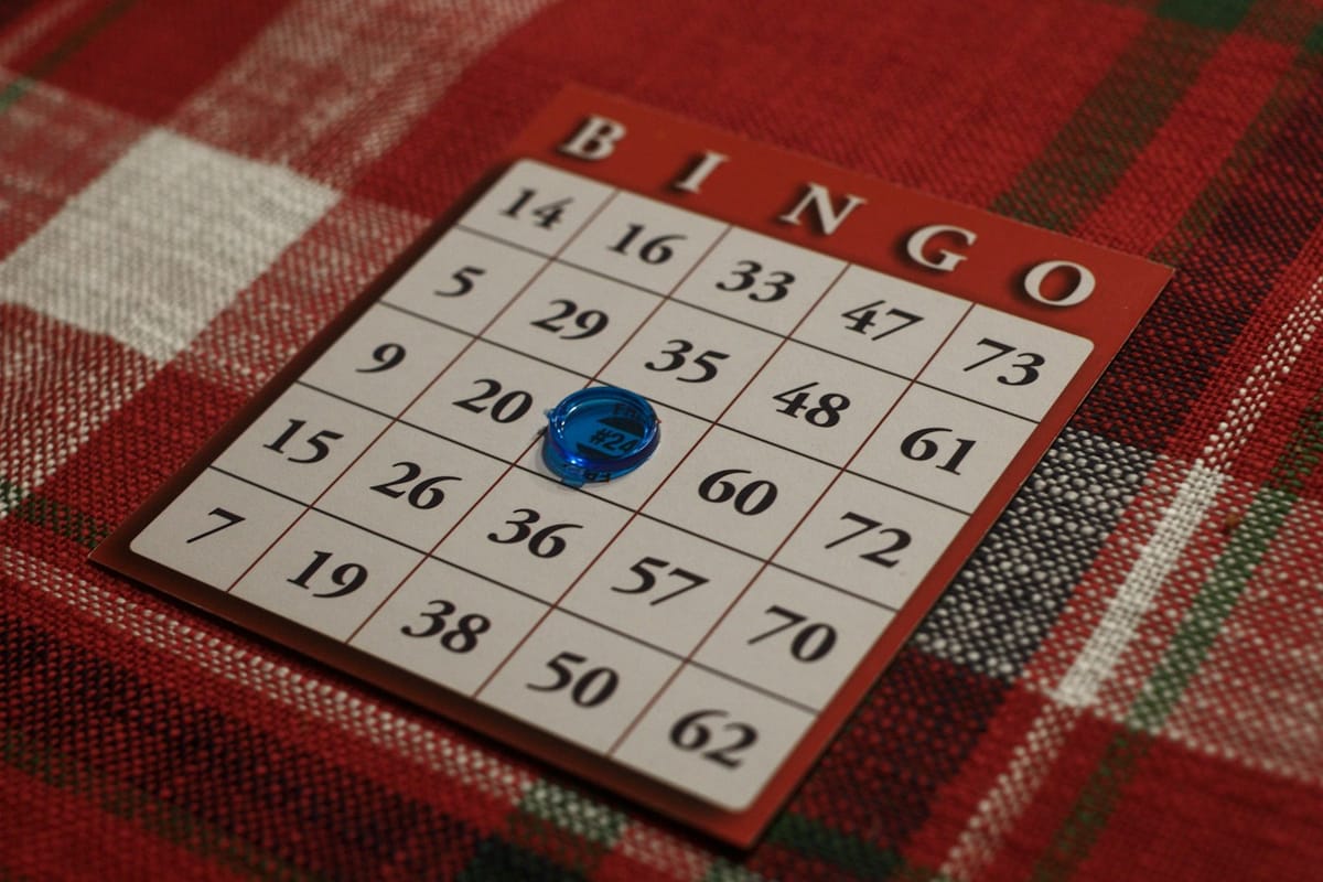 A paper bingo card with a blue dauber on a red tartan cloth