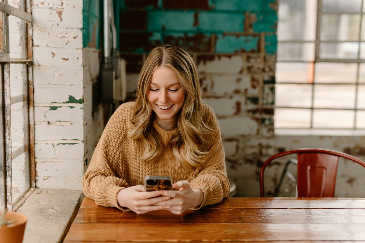 A woman at a café table looking at her phone